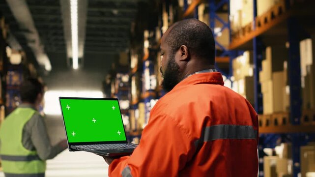 Mockup screen on laptop in industrial warehouse with black worker performing order fulfillment tasks. Workforce create professional logistics setting ready for e-commerce shipment.