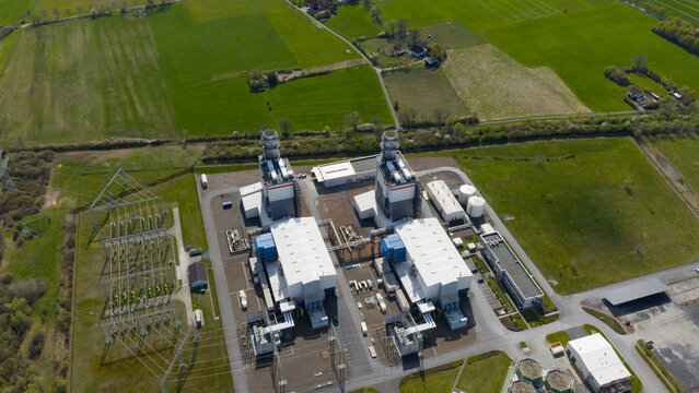 Aerial view of the Trianel Gaskraftwerk Hamm gas power plant with its industrial facility and electrical substation surrounded by green fields in Hamm, Nordrhein-Westfalen, Germany.