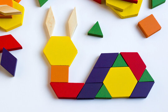 Colorful tangram puzzle game in the shape of a snail, with geometric pieces on a white surface.