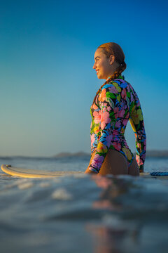 happy woman with surfboard looking at sunset