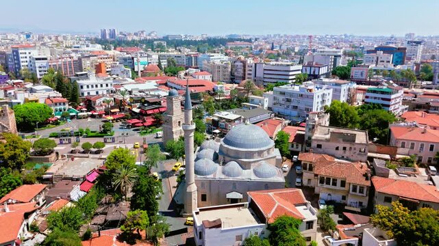 Drone view of Antalya, Turkey Yivli Minare Mosque area. Old town rooftops, green trees and historic skyline create a sunny travel scene.