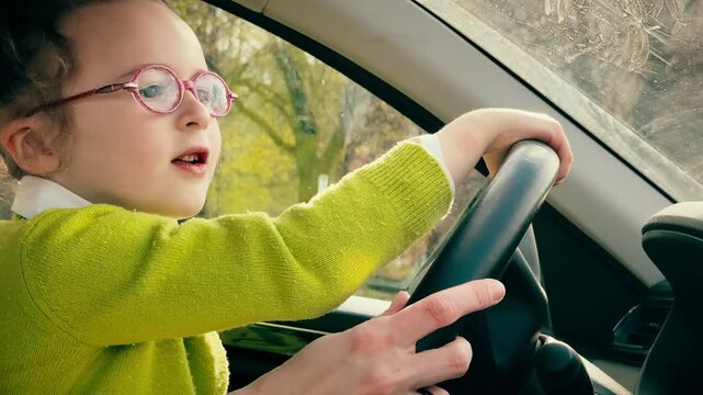 Child learning to drive car under adult supervision, hands on steering wheel close-up