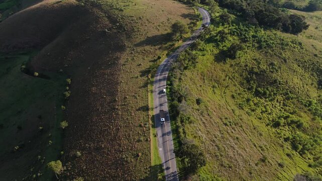 Drone capturando o movimento de autom&oacute;veis  estrada sinuosa entre morros da Serra da Mantiqueira.	
