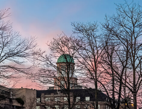 Copenhagen, Denmark - December 31, 2025: Axelborg tower with green dome under winter sunset colored sky, seen through foliage-less trees. Axelborg, located across the street from Tivoli Gardens on Ves