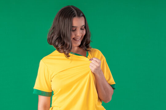 A Brazilian woman, a football fan, wears a Brazil jersey for the World Cup against a green background.