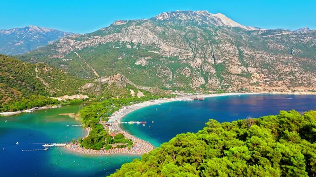 Drone view of Oludeniz Blue Lagoon, Turkey and mountains. Turquoise bay, green hills and sunny coastline create a scenic vacation view.