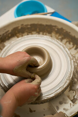 Fototapeta premium Artisan hands molding wet clay on a spinning pottery wheel in a studio close up.