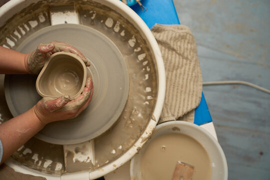 Close up of an artisan dealing with a collapsed clay pot on a pottery wheel.