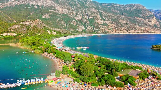 Drone view of Oludeniz Blue Lagoon, Turkey. Curved beach, turquoise water and green hills create a sunny Mediterranean travel scene.