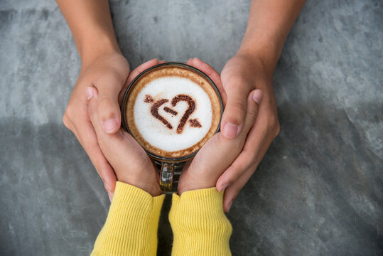 Close up Hands holding coffee cup. Couple lover drinking cup of coffee latte art together. Top view hands two people happy in cafe coffee shop. Espresso shot Young couple happy date relaxing in cafe