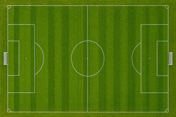 Aerial top down view of a green soccer field with white markings and goals, football pitch for sports competition and athletic recreation background © Patrick