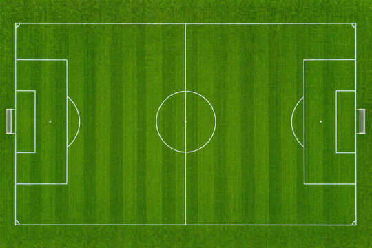 Aerial view of a green soccer field with white markings and mowed grass stripes, top down perspective of a football pitch for sports competition and athletic recreation