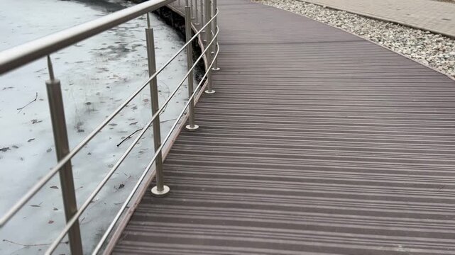 Icy reservoir jetty with steel railings, textured boardwalk and thin shore ice, overcast sky and muted tones, industrial detail