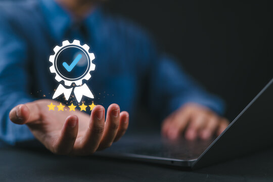 Hand showing quality assurance badge with guarantee and standards icons, representing ISO certification, product and service standards, customer satisfaction, and trusted service experience.