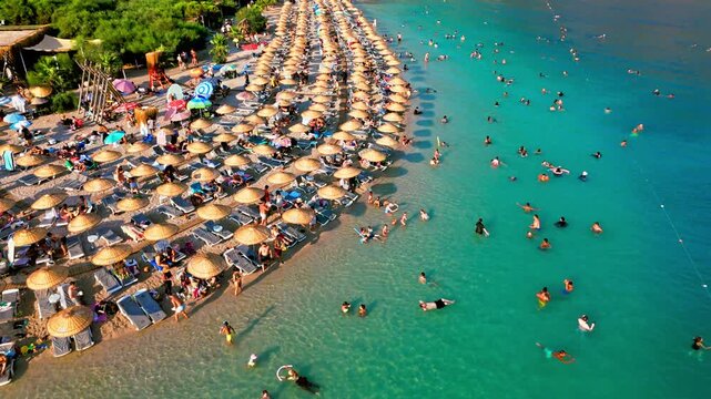 Aerial view of Oludeniz Blue Lagoon, Turkey umbrellas. People relax on the beach beside turquoise water in a sunny summer vacation scene.