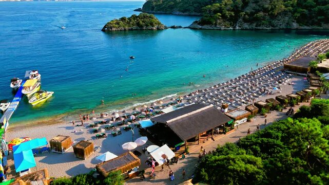Aerial view of Oludeniz Blue Lagoon, Turkey beach area. Umbrellas, boats, blue water and green hills create a sunny summer travel scene.