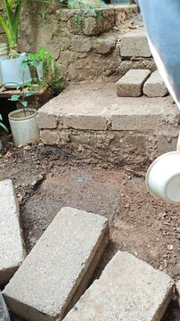 Man pouring water on dirt floor for dust control and soil compaction