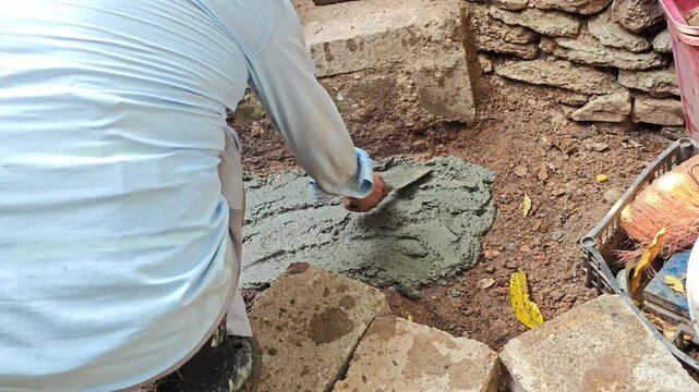 Spreading cement mixture over a dirt ground