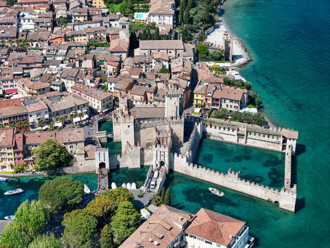 Aerial view of the Scaliger Castle and the historic town center surrounded by the turquoise waters of Lake Garda in Sirmione, Lombardy, Italy.