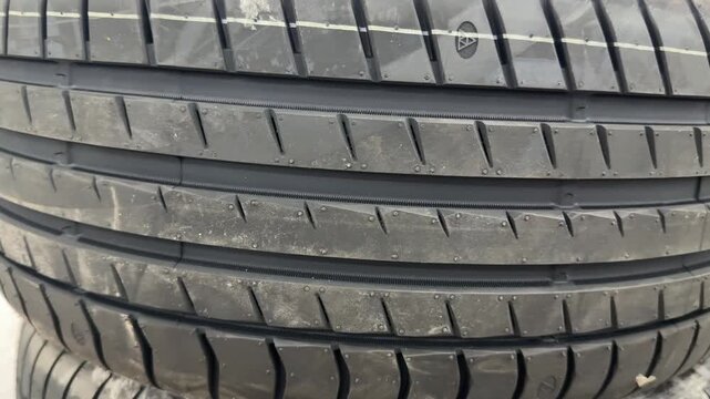 Stacked summer tires at dealership close-up showing clear tread patterns and rubber texture, passenger car sizes arranged in neat