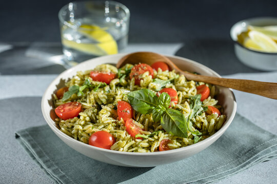 Salad with orzo pasta, arugaula, pesto sauce, and sun-dried tomatoes