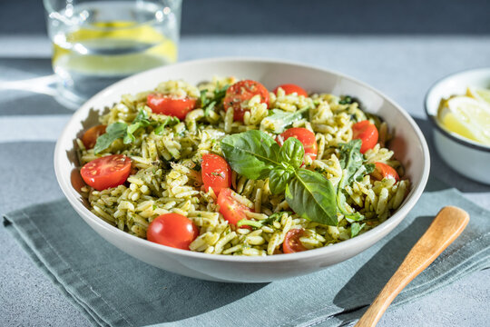Salad with orzo pasta, arugaula, pesto sauce, and sun-dried tomatoes
