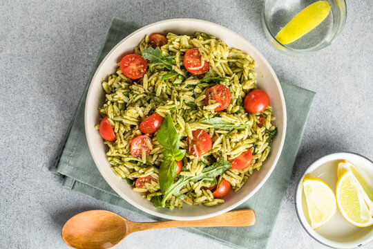Salad with orzo pasta, arugaula, pesto sauce, and sun-dried tomatoes