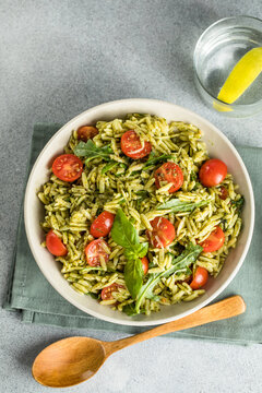 Salad with orzo pasta, arugaula, pesto sauce, and sun-dried tomatoes