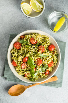 Salad with orzo pasta, arugaula, pesto sauce, and sun-dried tomatoes