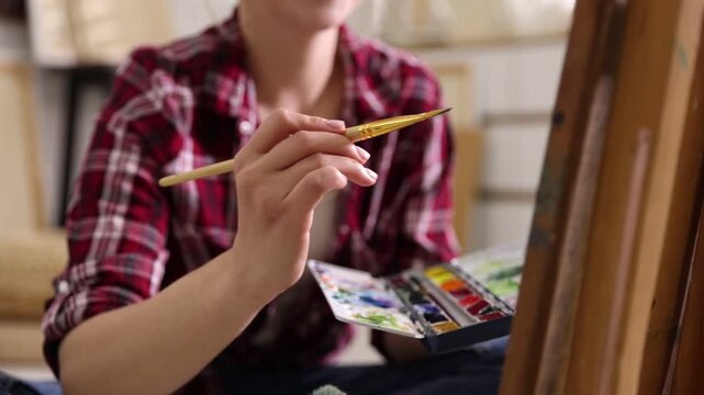 Woman painting with brush in studio, camera moving out. Slow motion effect