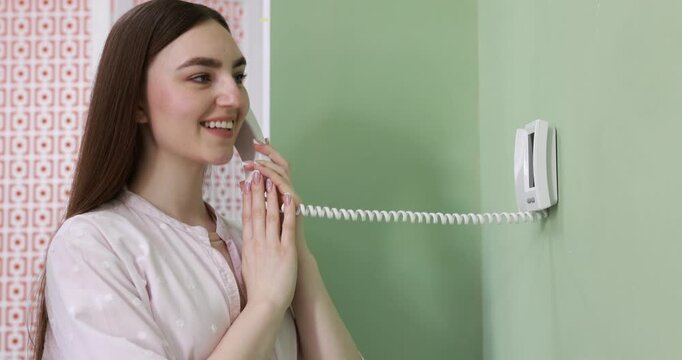 Young woman answering intercom call at home