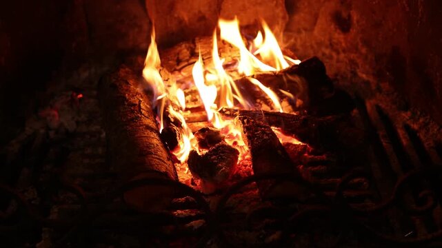 Woman poking logs in fireplace at home, closeup
