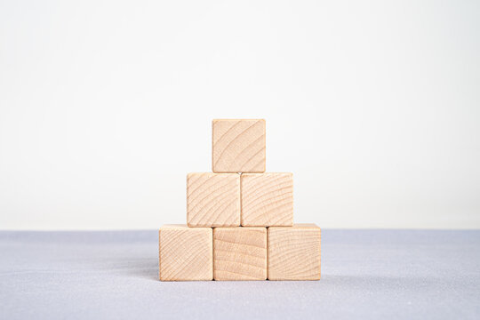 Stack of blank wooden cubes forming a rising staircase or bar graph. Symbolic of growth, career advancement, financial success, and step-by-step development.