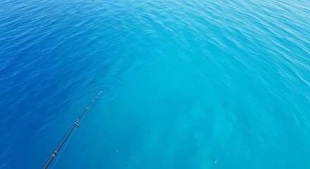 Naklejka premium A high-angle view of blue sea water with a single fishing rod extending over the side of a boat, leaving plenty of open room for content, tranquil, gear, summer