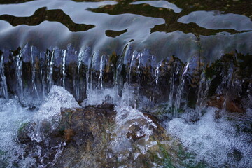 Clear water flowing over rocks creating small cascades © Gloream