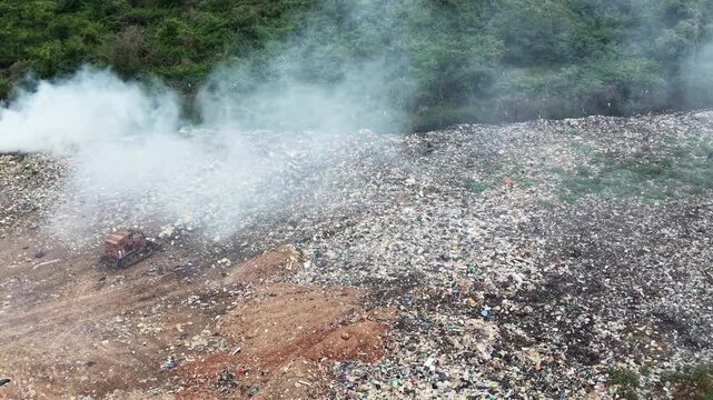 Lix&atilde;o a c&eacute;u aberto com fuma&ccedil;a t&oacute;xica e degradante impacto ambiental. Vista panor&acirc;mica de aterro sanit&aacute;rio irregular (lix&atilde;o) liberando fuma&ccedil;a no meio da vegeta&ccedil;&atilde;o. lixo se acumula, causando polui&ccedil;&atilde;o.