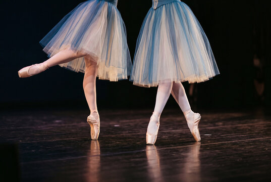 Legs of two ballet dancers on pointe shoes on stage