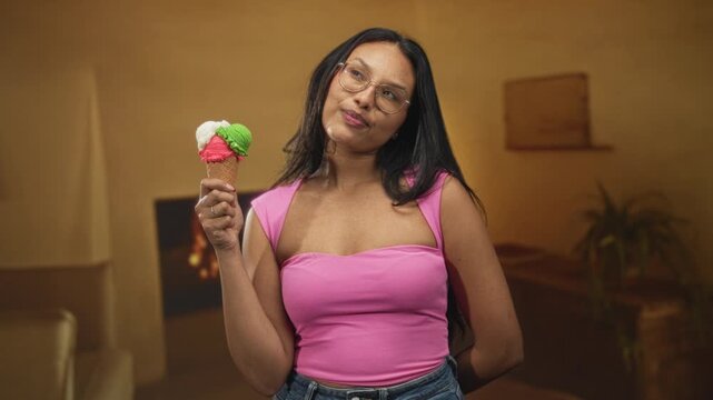 Woman holding a three scoop ice cream cone, lips pursed and head tilted while wearing glasses in a studio living room set; playful curiosity.