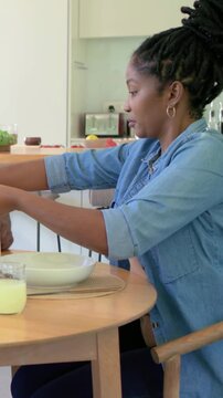 Vertical video: Reaching woman wearing denim preparing meal at home, placing white bowl and glass