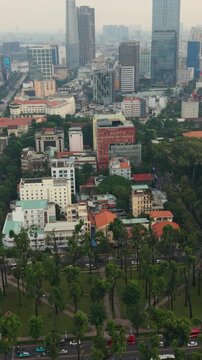 Vertical screen, Vietnam, Ho Chi Minh Aerial View Saigon Old District Showing Dense Lowrise Houses And Redtiled Roofs Beside Distant Glass Skyscrapers, Treelined Boulevard With Slow Traffic,