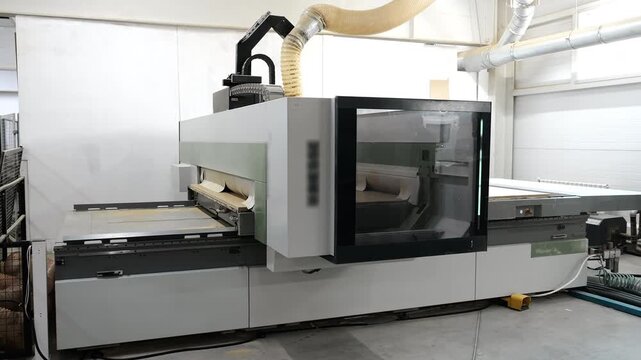 Large industrial CNC woodworking machine operating in modern furniture manufacturing workshop.
