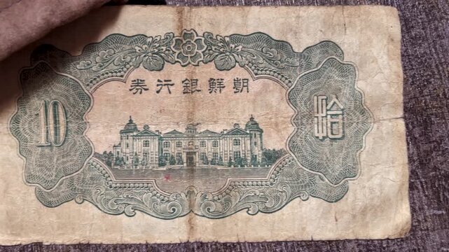 Reverse side of an antique East Asian 10 yen banknote, featuring an engraved building illustration, ornate decorative borders, aged paper texture, and detailed vintage currency design.