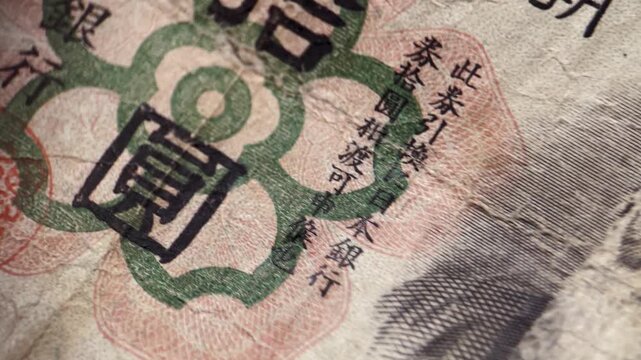 Close up video of an antique Japanese 10 yen banknote highlighting the decorative numeral, intricate printed pattern, aged paper texture, and detailed vintage currency design.