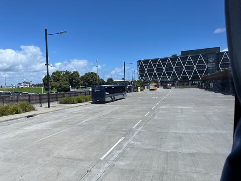 Manukau Institute of Technology (MIT) campus building and AT Metro bus at the Manukau Bus Station transport hub under blue skies - Auckland, New Zealand, February 07, 2023
