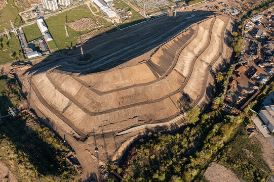 Brasov, Romania - 28 April 2026: Aerial view of a large terraced earthwork site in an industrial area with power lines and green fields.