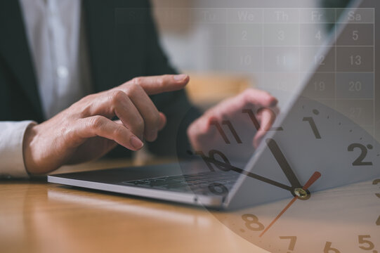 Effective time management and scheduling of company work hours concept. Working hours and working overtime. Close-up view of an employee typing on a computer with a clock overlapping.