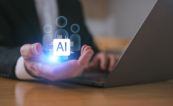 Business man hand holding ai icon and people pegs and using computer laptop working with AI technology for Human Resources recruitment program. using ai tech as an assistant at work.