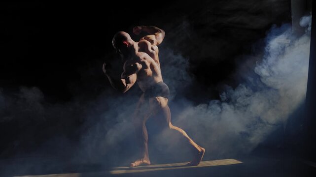A male bodybuilder poses in shorts, showing off his muscles. 