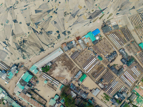 Cox's Bazar, Bangladesh - 11 March 2026: Aerial view of fishing nets spread on the sand and traditional coastal buildings in a fishing village.