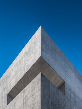 Minimalist modern concrete building corner with geometric architecture detail against vibrant clear blue sky background
